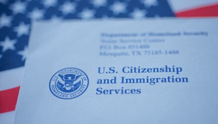 Hand touching Letter (Envelope) from USCIS on  flag of USA background.