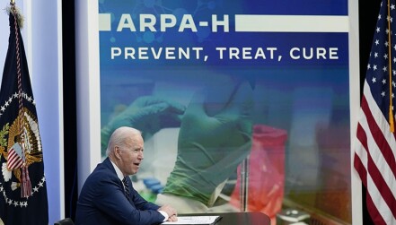 Biden, seated and in profile, in front of a backdrop that reads "ARPA-H: Prevent, treat, cure"