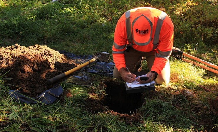 A geophysicist from the USGS Cascades Volcano Observatory notes the location of a newly buried seismometer on Mount Rainier in Washington. The observatory was established after the eruption of Mount St. Helens in 1980.  (Image credit – Elizabeth Westby / USGS)