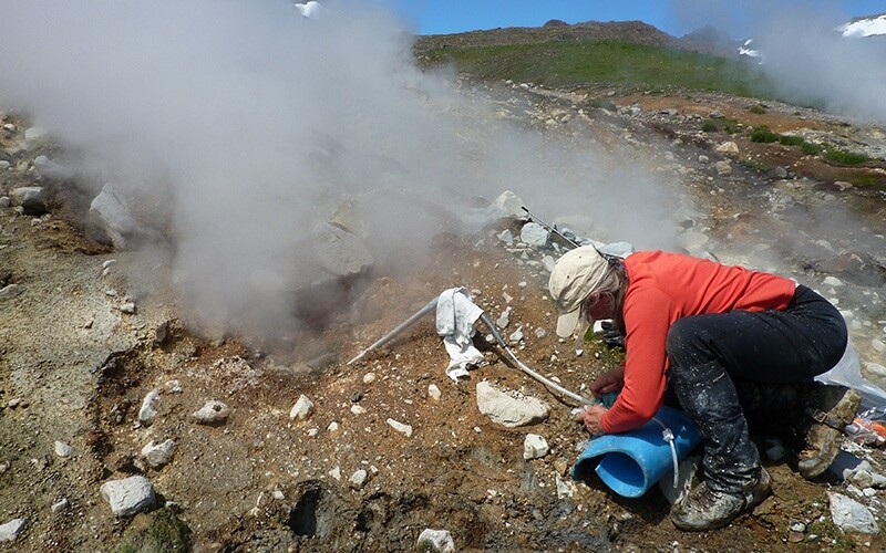 A USGS scientist collects a gas sample on the flank of Akutan Volcano in Alaska